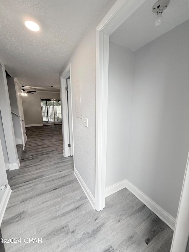 corridor featuring light hardwood / wood-style flooring and a textured ceiling