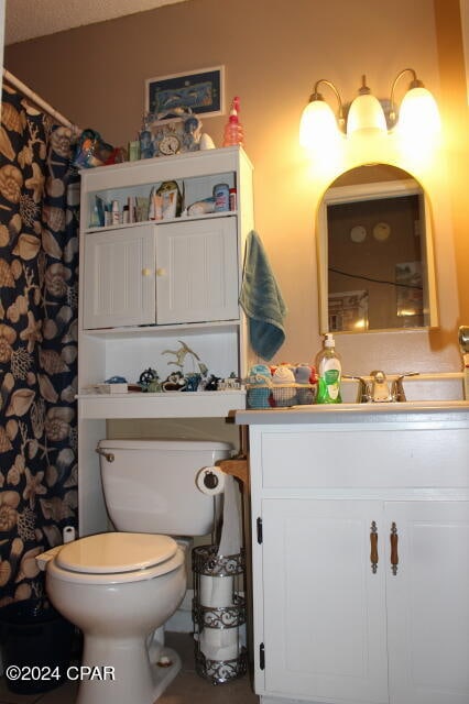 bathroom with a textured ceiling, vanity, and toilet