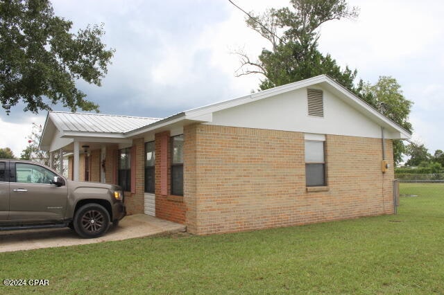 view of side of property featuring a yard and a carport