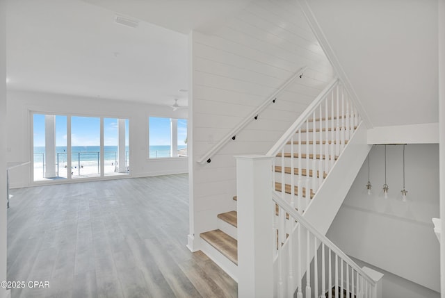 stairway with wood finished floors, visible vents, and a water view