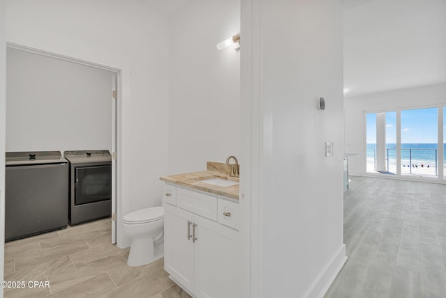 bathroom featuring a water view, toilet, vanity, and washer and clothes dryer