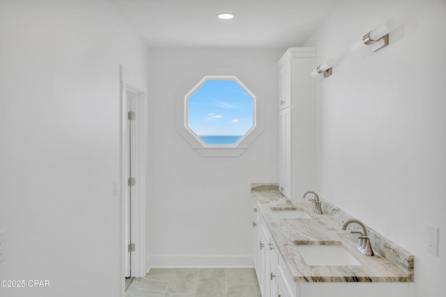 bathroom featuring double vanity, baseboards, and a sink