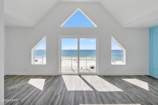 unfurnished living room featuring high vaulted ceiling, dark wood-style flooring, a water view, and baseboards