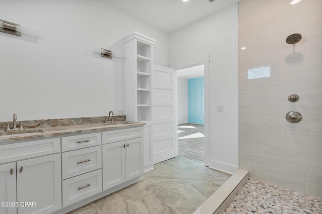 full bath featuring tiled shower, baseboards, and a sink