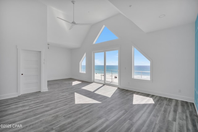 unfurnished living room featuring a water view, high vaulted ceiling, a ceiling fan, dark wood-style floors, and baseboards