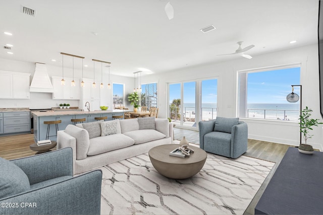 living room with baseboards, recessed lighting, visible vents, and light wood-type flooring