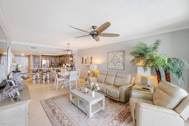 living room with ceiling fan, a textured ceiling, light wood-type flooring, and crown molding