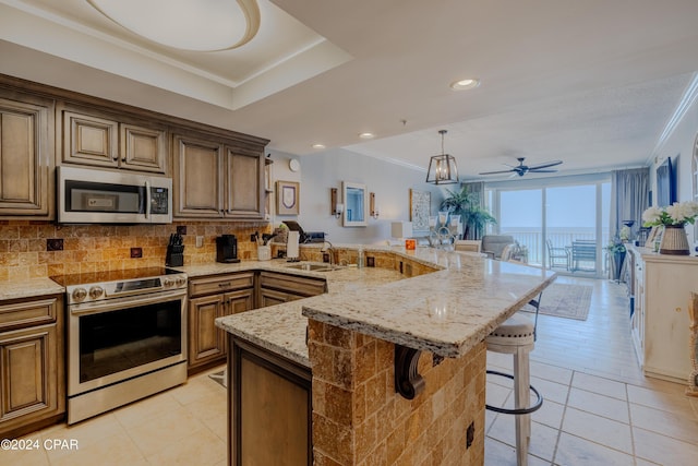 kitchen featuring open floor plan, stainless steel appliances, a breakfast bar, and ornamental molding