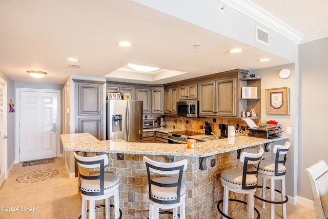 kitchen featuring light stone counters, appliances with stainless steel finishes, a breakfast bar area, a peninsula, and open shelves