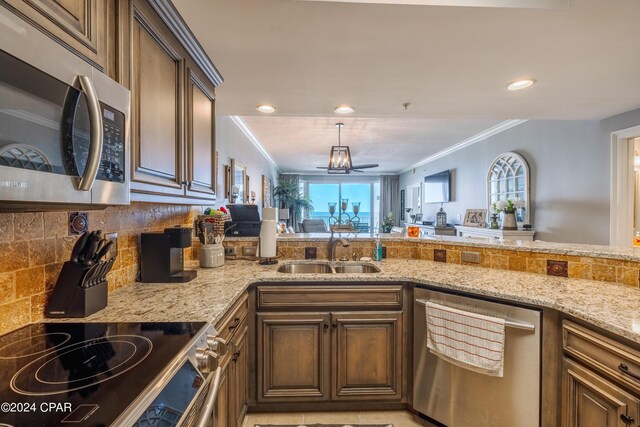 kitchen featuring appliances with stainless steel finishes, light stone countertops, ornamental molding, and sink