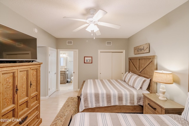 bedroom featuring light wood-type flooring, a closet, a textured ceiling, ensuite bath, and ceiling fan