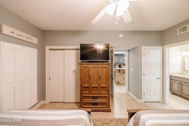 bedroom featuring a closet, visible vents, light wood-style flooring, a ceiling fan, and a textured ceiling