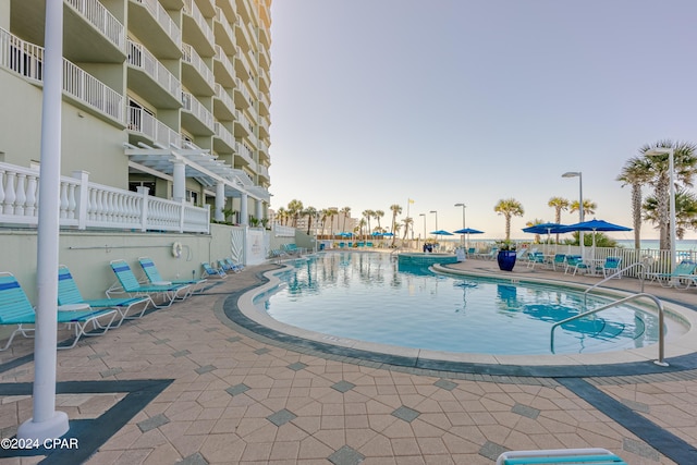 community pool with a patio area and fence