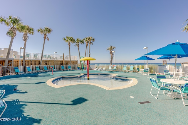 view of play area featuring a water view, fence, a hot tub, and a community pool