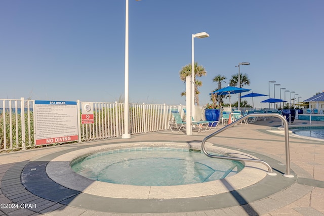 view of swimming pool featuring a community hot tub and fence