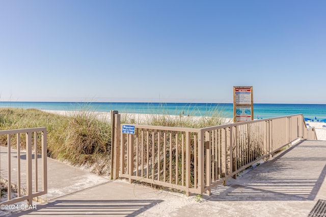 view of water feature featuring a beach view and a gate