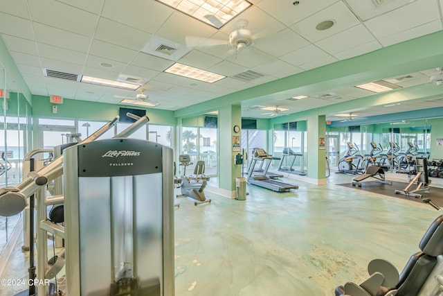 gym featuring baseboards, visible vents, ceiling fan, and a drop ceiling