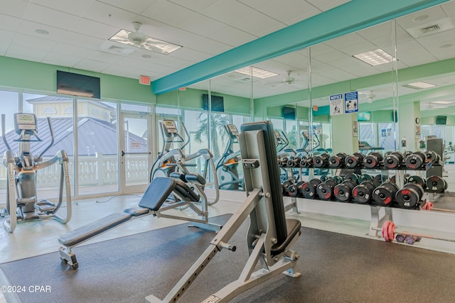 exercise room with a paneled ceiling, ceiling fan, and visible vents