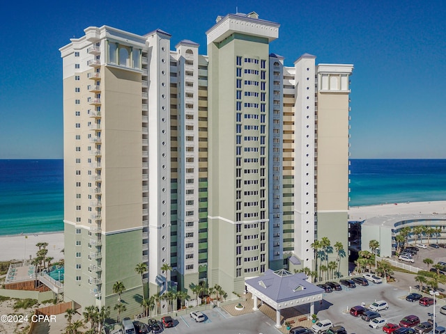 view of building exterior featuring uncovered parking, a beach view, and a water view