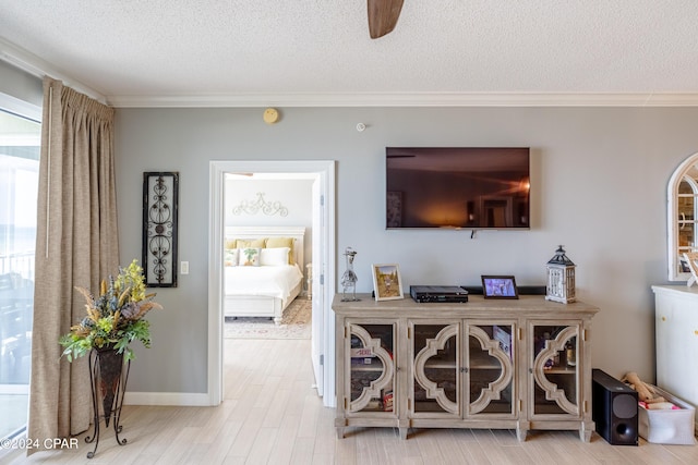 living room featuring a textured ceiling, baseboards, wood finished floors, and crown molding