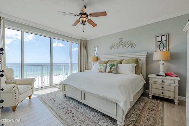 bedroom with light hardwood / wood-style floors, a water view, ceiling fan, access to outside, and ornamental molding