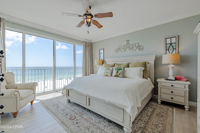 bedroom with a water view, access to exterior, light wood-type flooring, and ornamental molding