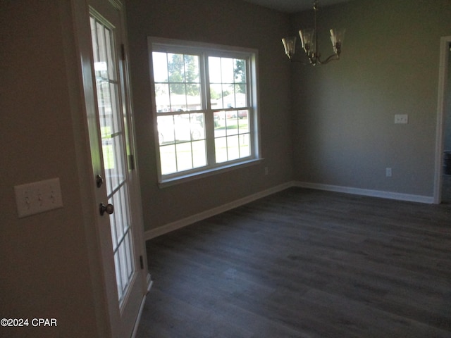 unfurnished room featuring an inviting chandelier and dark hardwood / wood-style flooring