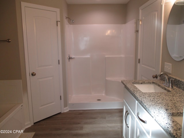 bathroom with walk in shower, vanity, and hardwood / wood-style flooring