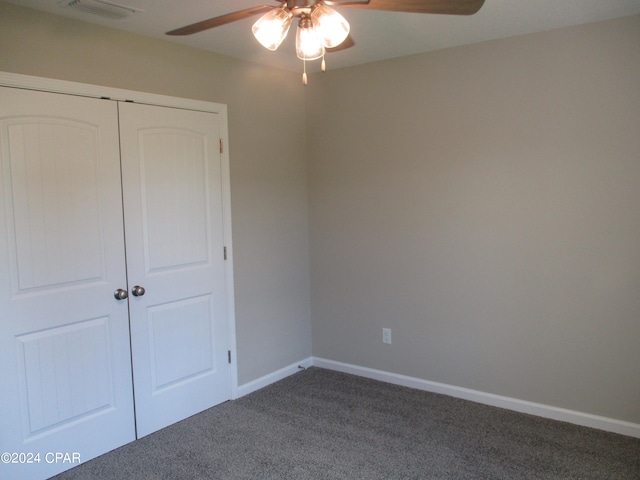 unfurnished bedroom featuring ceiling fan, a closet, and dark carpet