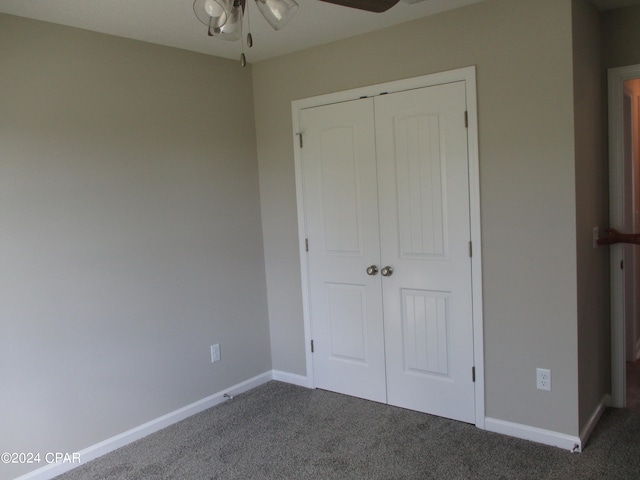 unfurnished bedroom featuring ceiling fan, a closet, and dark carpet