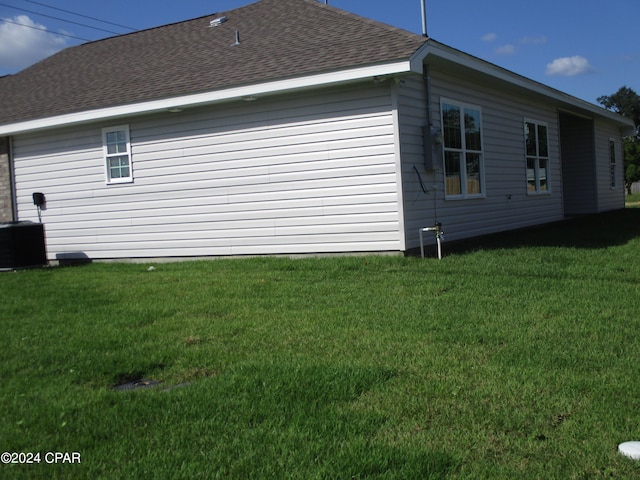 view of side of home featuring cooling unit and a lawn