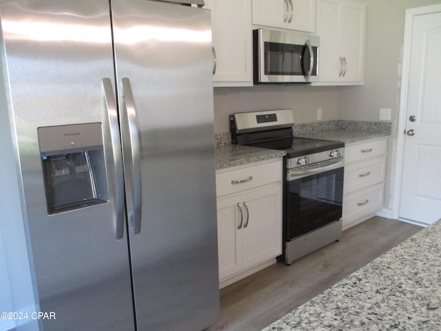 kitchen featuring stainless steel appliances, white cabinetry, light hardwood / wood-style floors, and light stone counters