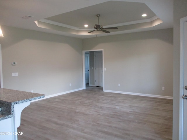 interior space featuring a raised ceiling, hardwood / wood-style floors, and ceiling fan