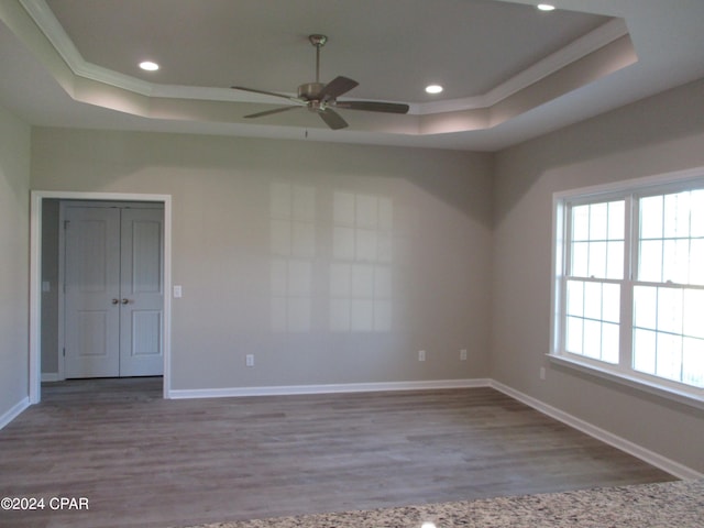 unfurnished room with ceiling fan, ornamental molding, a tray ceiling, and light hardwood / wood-style floors