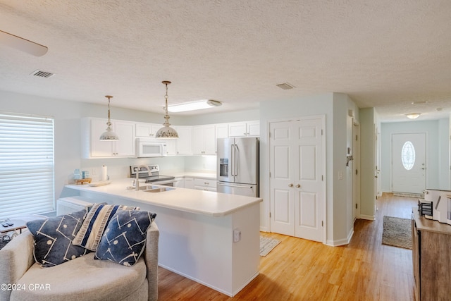 kitchen with kitchen peninsula, appliances with stainless steel finishes, a textured ceiling, pendant lighting, and light hardwood / wood-style flooring