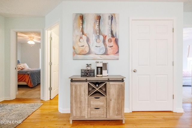 bar featuring light brown cabinetry, a textured ceiling, light hardwood / wood-style flooring, and ceiling fan