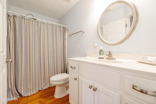 bathroom featuring walk in shower, a textured ceiling, toilet, vanity, and hardwood / wood-style flooring