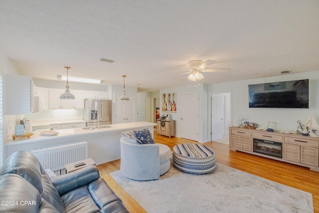 living room featuring a textured ceiling, light hardwood / wood-style flooring, and ceiling fan