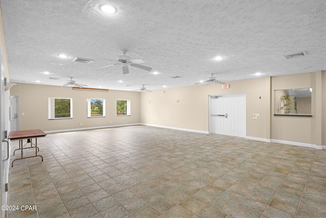 unfurnished living room with ceiling fan and a textured ceiling