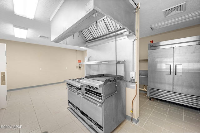 kitchen featuring gas range oven, a textured ceiling, and refrigerator