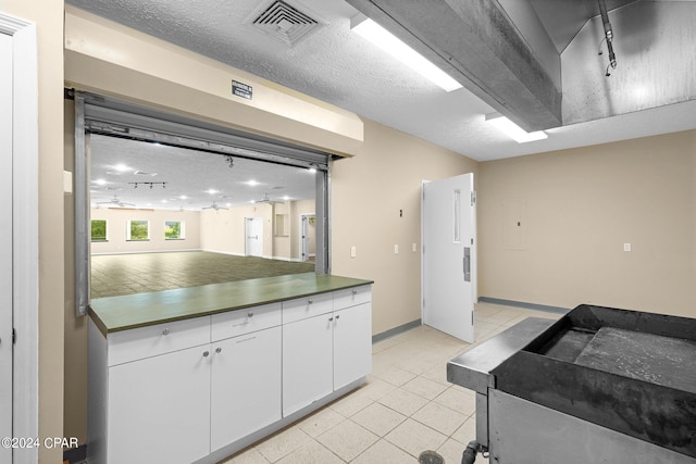 kitchen with white cabinets, a textured ceiling, and light tile patterned flooring