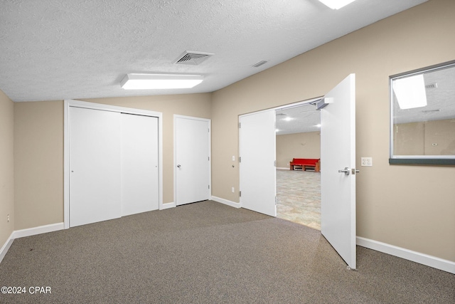 unfurnished bedroom featuring a textured ceiling, carpet, and vaulted ceiling