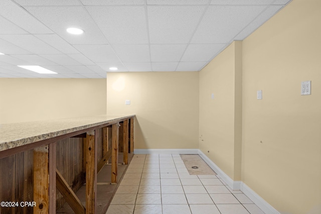 corridor with a drop ceiling and light tile patterned floors