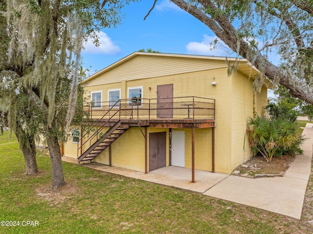 rear view of house featuring a wooden deck and a lawn