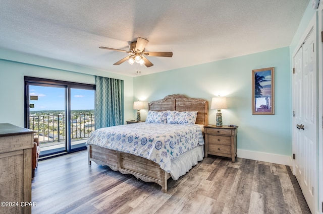 bedroom featuring ceiling fan, hardwood / wood-style floors, a closet, access to outside, and a textured ceiling