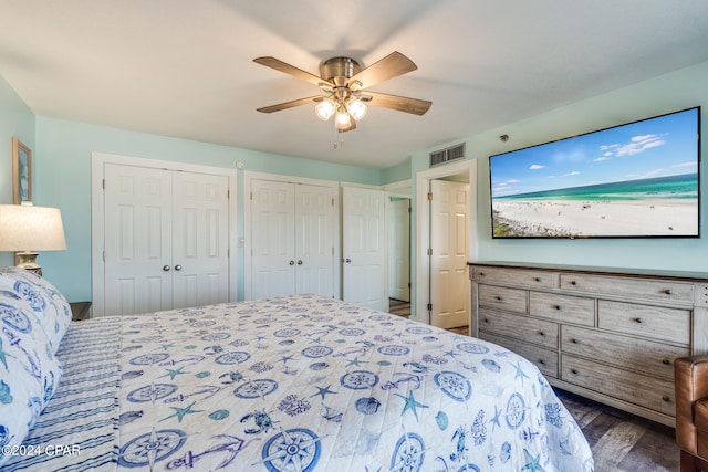 bedroom featuring ceiling fan, dark wood-type flooring, and two closets