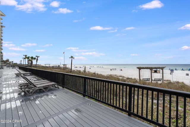 wooden deck featuring a water view and a beach view