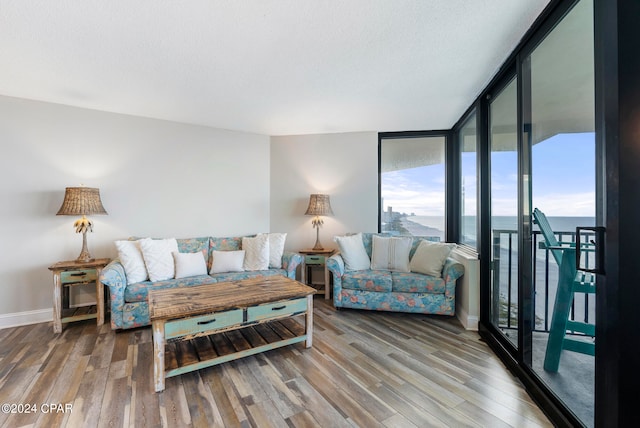 living room with a wall of windows, a water view, and hardwood / wood-style flooring