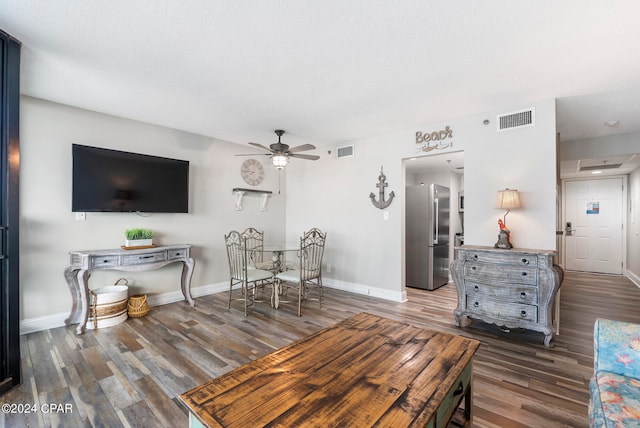 living room featuring a textured ceiling, ceiling fan, and dark wood-type flooring