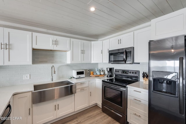 kitchen with sink, white cabinetry, light wood-type flooring, appliances with stainless steel finishes, and ornamental molding